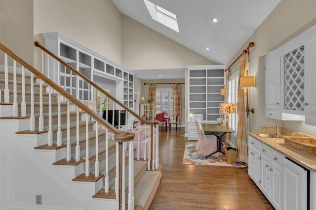 staircase featuring a skylight, high vaulted ceiling, wood finished floors, and recessed lighting