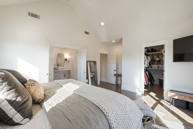 bedroom featuring a walk in closet, ensuite bath, high vaulted ceiling, dark hardwood / wood-style floors, and a closet