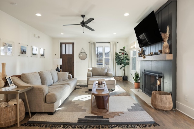 living room featuring a fireplace, light hardwood / wood-style floors, and ceiling fan