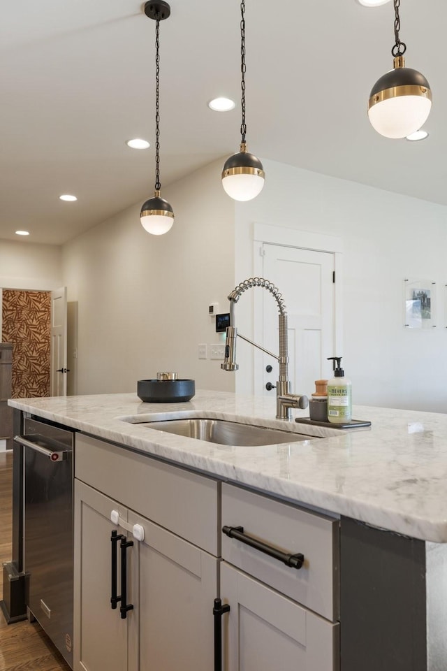 kitchen with dark wood-type flooring, sink, light stone counters, stainless steel dishwasher, and pendant lighting