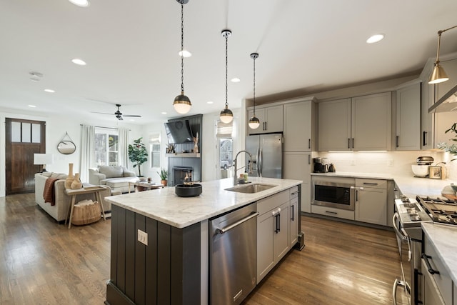 kitchen with a center island with sink, gray cabinets, and appliances with stainless steel finishes