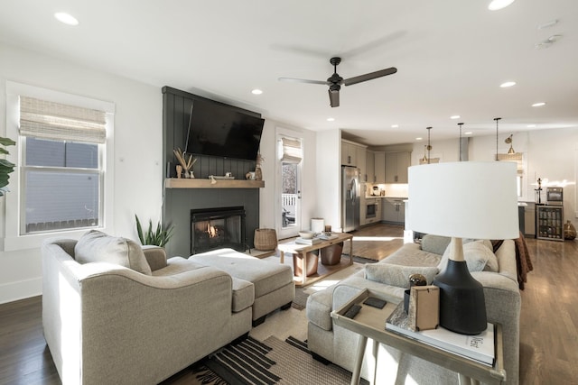 living room with hardwood / wood-style floors, a large fireplace, and ceiling fan