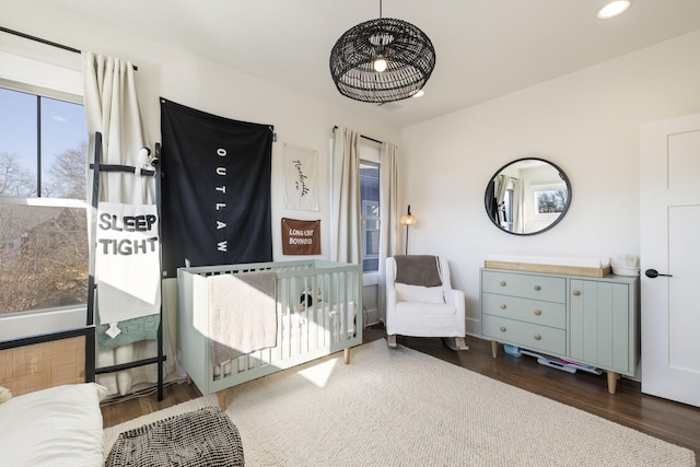 bedroom with dark hardwood / wood-style floors and a nursery area