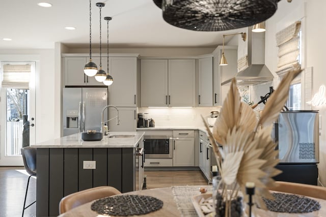 kitchen with tasteful backsplash, sink, stainless steel fridge, hardwood / wood-style flooring, and a kitchen island with sink