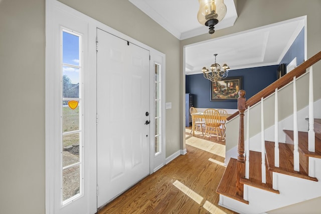 foyer featuring an inviting chandelier, ornamental molding, and wood-type flooring