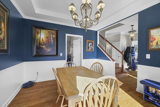 dining room with dark hardwood / wood-style flooring, ornamental molding, an inviting chandelier, and a tray ceiling