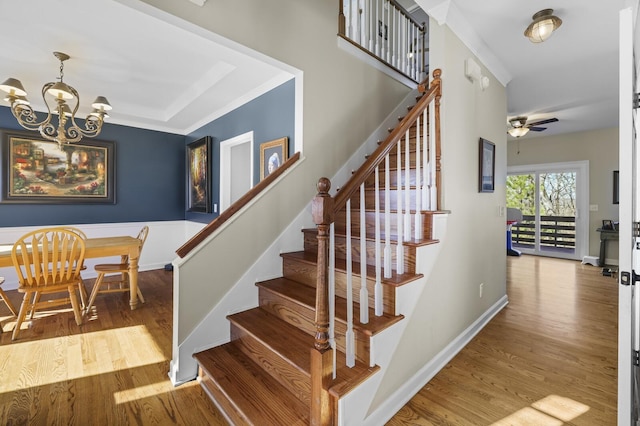 stairway with hardwood / wood-style flooring and ceiling fan with notable chandelier