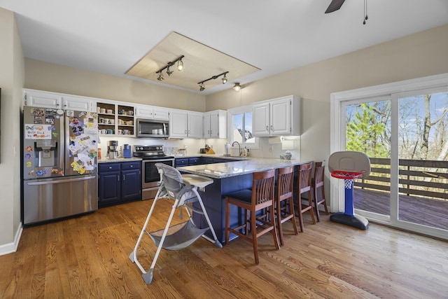 kitchen with blue cabinetry, appliances with stainless steel finishes, light hardwood / wood-style flooring, and white cabinets