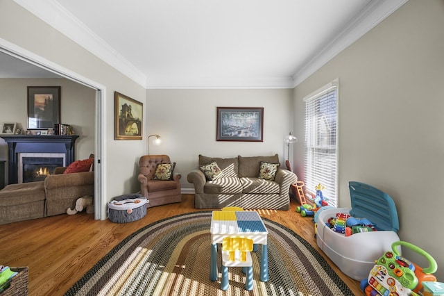 living room featuring a tiled fireplace, hardwood / wood-style flooring, and crown molding