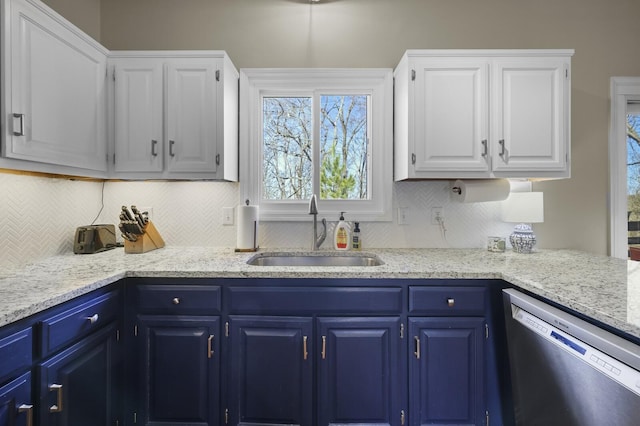 kitchen featuring stainless steel dishwasher, blue cabinets, sink, and white cabinets