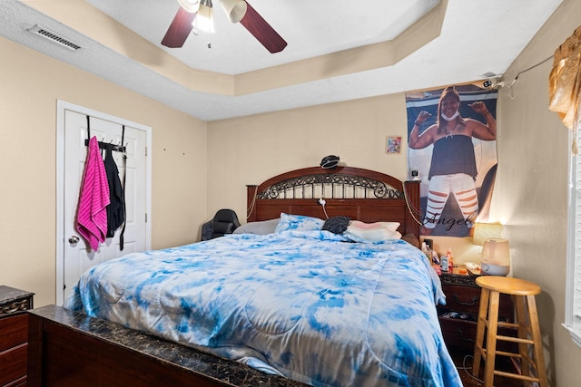 bedroom featuring a tray ceiling, a closet, and ceiling fan