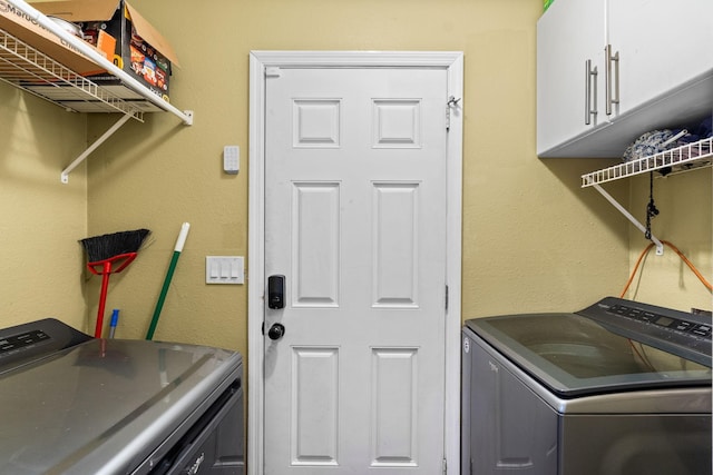 washroom with cabinets and washing machine and clothes dryer