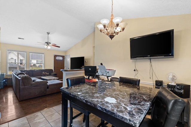 tiled dining space with ceiling fan with notable chandelier and vaulted ceiling