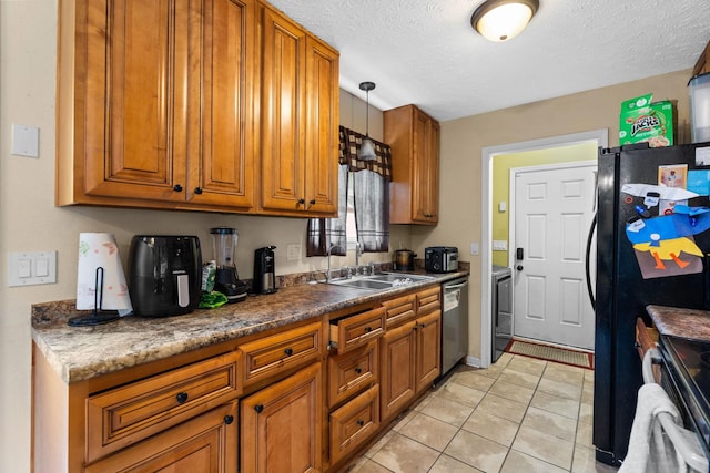 kitchen featuring washer / clothes dryer, sink, hanging light fixtures, light tile patterned floors, and stainless steel appliances