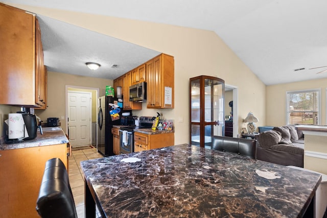 kitchen with stainless steel appliances, lofted ceiling, light tile patterned floors, and french doors