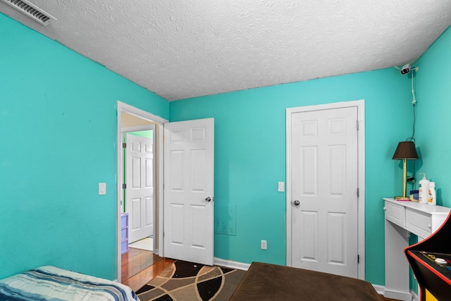 bedroom featuring wood-type flooring and a textured ceiling