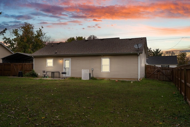 back house at dusk with a patio area and a lawn