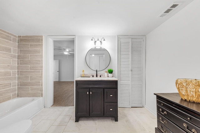 bathroom featuring vanity, toilet, and a tub to relax in