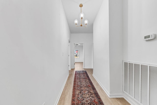 corridor featuring a chandelier and light wood-type flooring