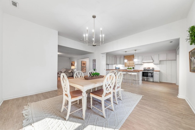 dining space with an inviting chandelier and light hardwood / wood-style floors