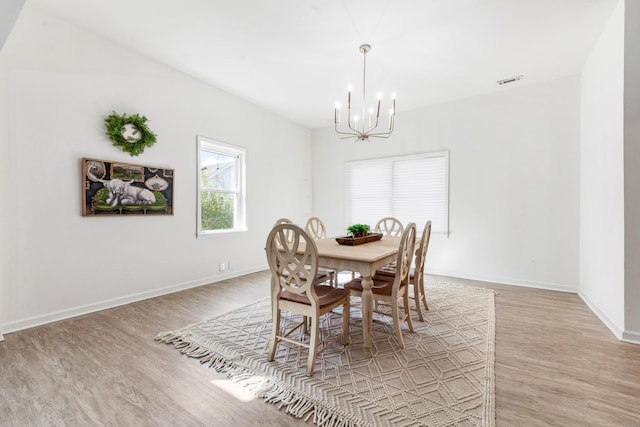 dining area with a notable chandelier and light hardwood / wood-style flooring