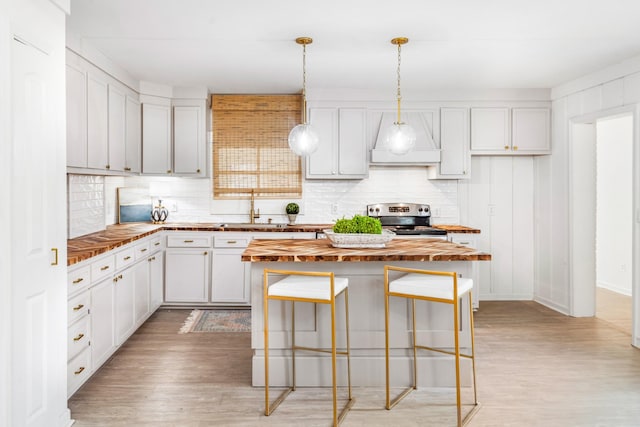 kitchen featuring decorative backsplash, white cabinets, hanging light fixtures, and electric range