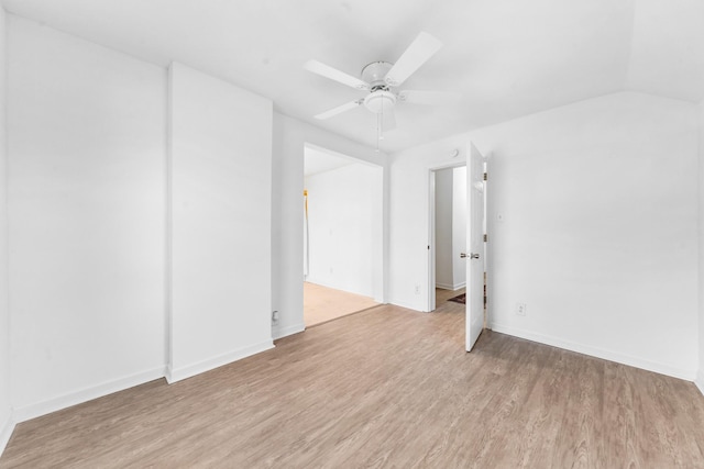 empty room with ceiling fan, vaulted ceiling, and light hardwood / wood-style flooring