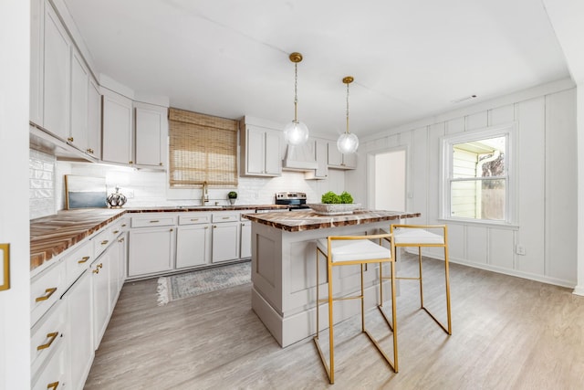 kitchen featuring white cabinetry, pendant lighting, light hardwood / wood-style floors, and a center island