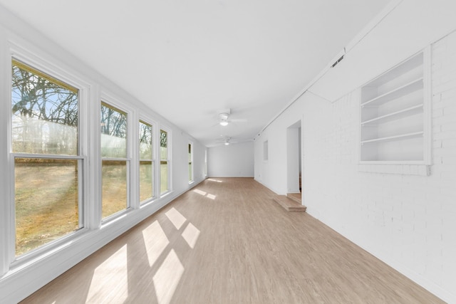 unfurnished sunroom featuring ceiling fan