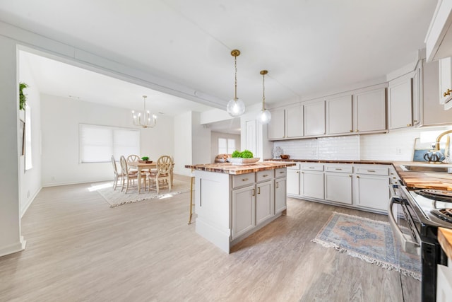 kitchen featuring decorative light fixtures, sink, a kitchen island, and stove