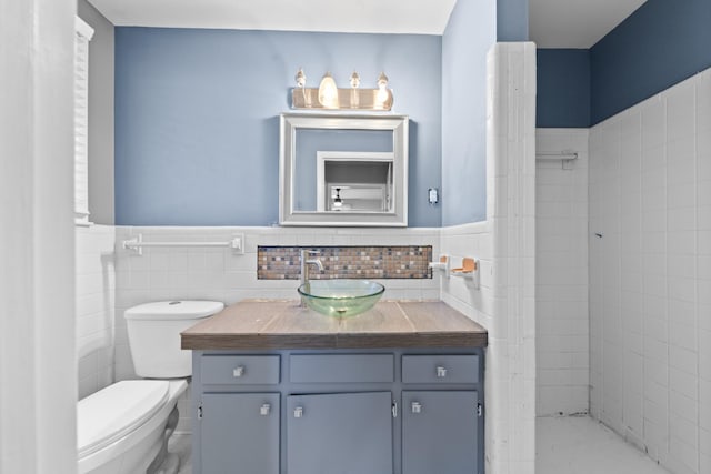 bathroom featuring vanity, tile walls, and toilet