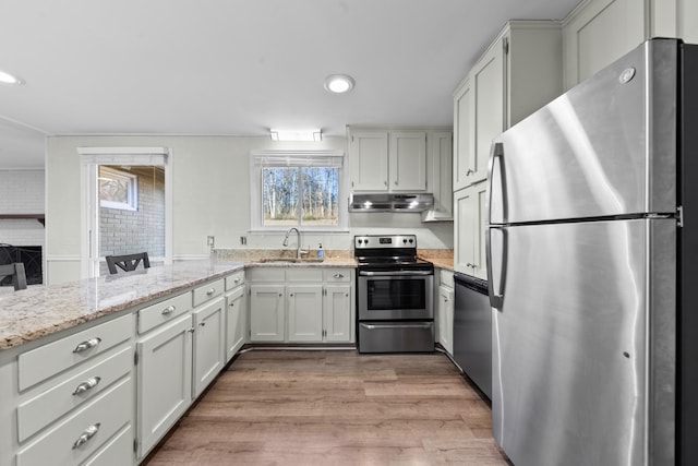 kitchen featuring sink, white cabinets, light stone counters, stainless steel appliances, and light wood-type flooring