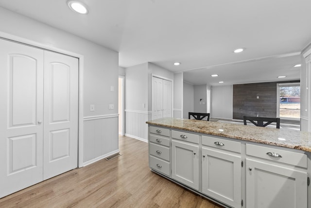 kitchen featuring white cabinetry, light stone countertops, and light hardwood / wood-style floors