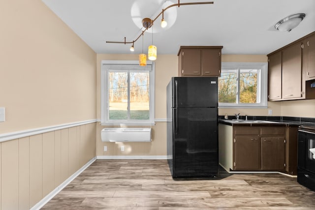 kitchen featuring light hardwood / wood-style flooring, dark brown cabinets, black appliances, and a wall unit AC