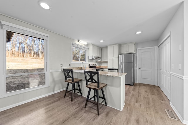 kitchen featuring a healthy amount of sunlight, appliances with stainless steel finishes, kitchen peninsula, and a breakfast bar area