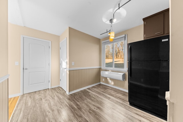 kitchen with black fridge, a wall mounted air conditioner, dark brown cabinets, and light hardwood / wood-style flooring