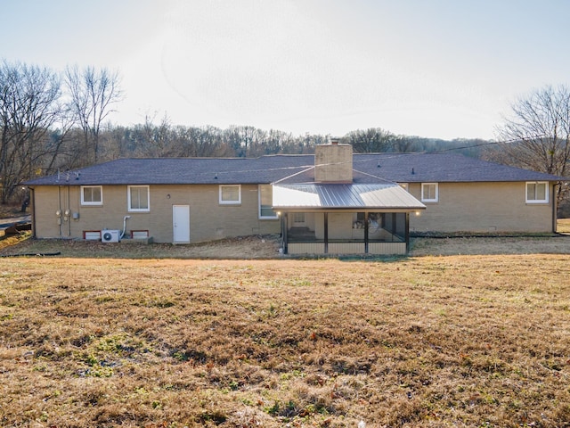 rear view of house featuring a lawn and a sunroom