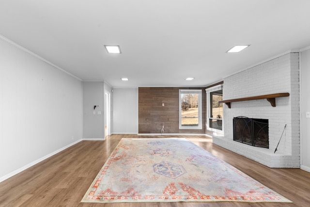 unfurnished living room with ornamental molding, wood-type flooring, and a brick fireplace