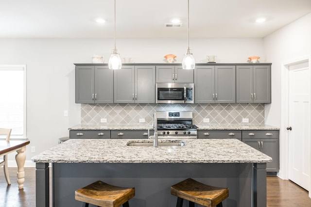 kitchen featuring gray cabinets, appliances with stainless steel finishes, and decorative light fixtures