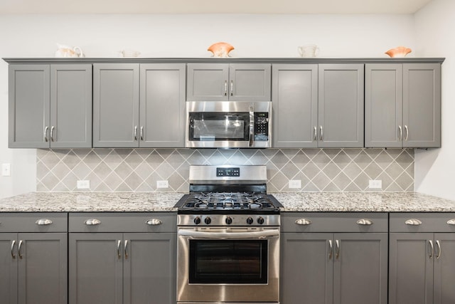 kitchen with gray cabinets, light stone countertops, and appliances with stainless steel finishes