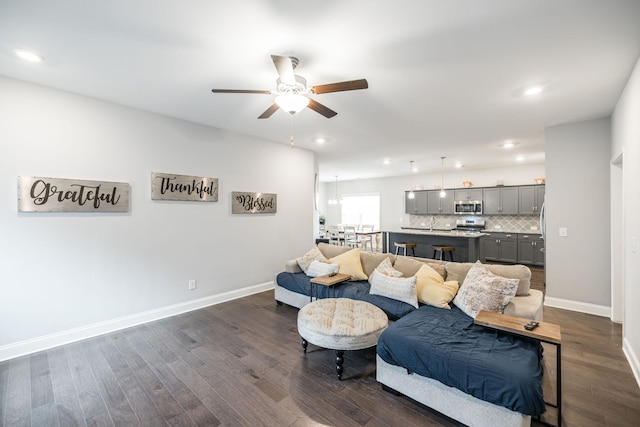 living room with dark wood-type flooring and ceiling fan