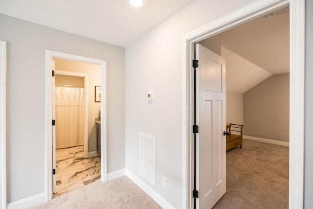 corridor featuring lofted ceiling and light colored carpet