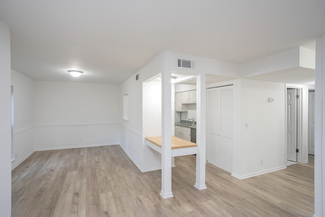 basement with sink and light hardwood / wood-style flooring