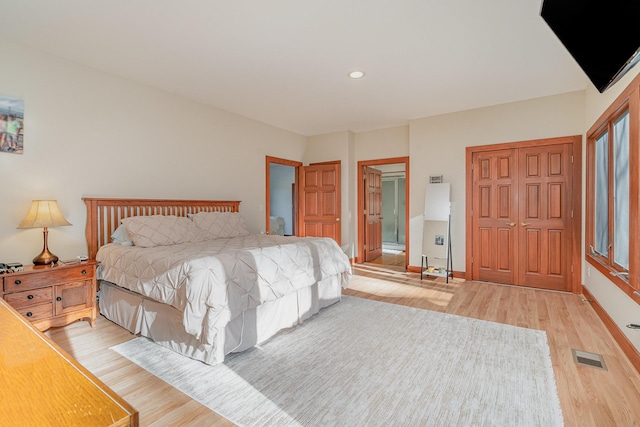 bedroom with connected bathroom and light hardwood / wood-style floors