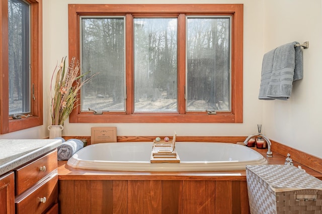 bathroom with a bathing tub, a healthy amount of sunlight, and vanity