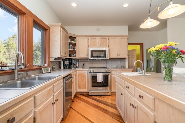 kitchen with sink, hanging light fixtures, stainless steel appliances, tile counters, and light brown cabinetry