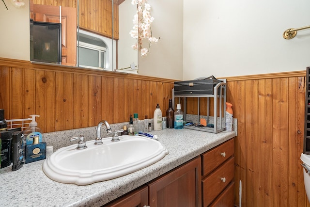 bathroom with vanity, toilet, and wood walls