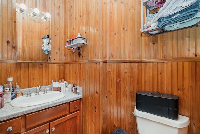 bathroom with wooden walls, vanity, and toilet