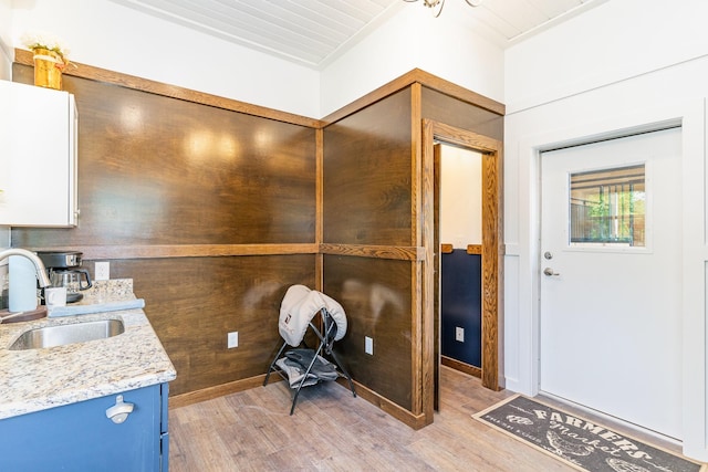 interior space with light stone counters, sink, blue cabinetry, and light wood-type flooring