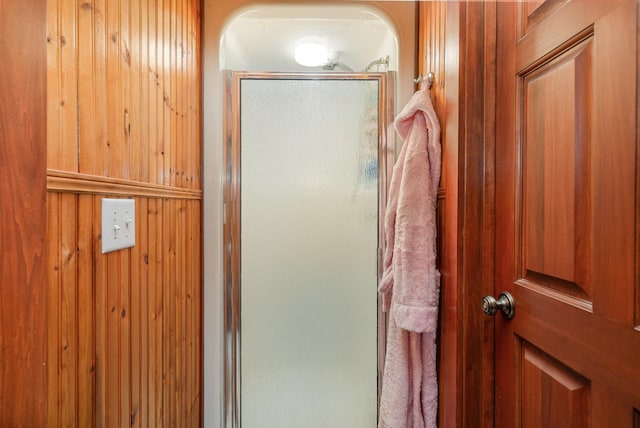 bathroom with an enclosed shower and wooden walls